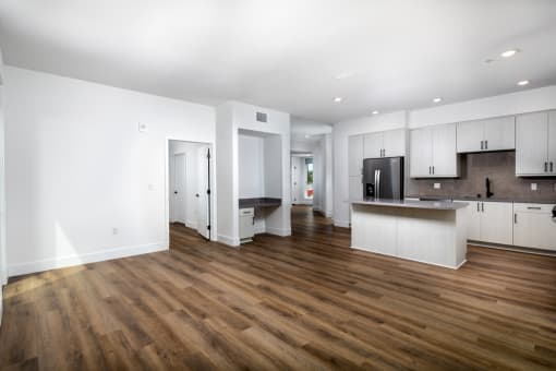 an open living room and kitchen with white walls and wood floors at VORA LUX, California, 92120