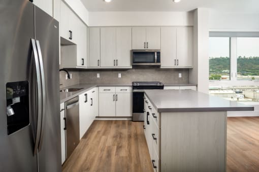 a kitchen with white cabinets and stainless steel appliances at VORA LUX, San Diego, CA