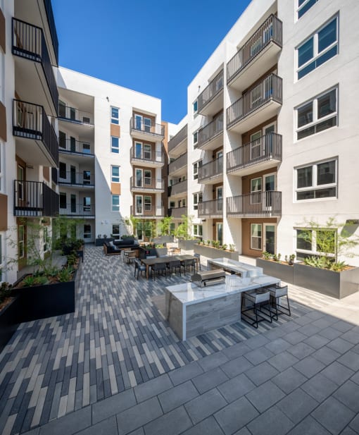 an outdoor patio with a firepit and tables surrounded by apartment buildings at VORA LUX, San Diego California