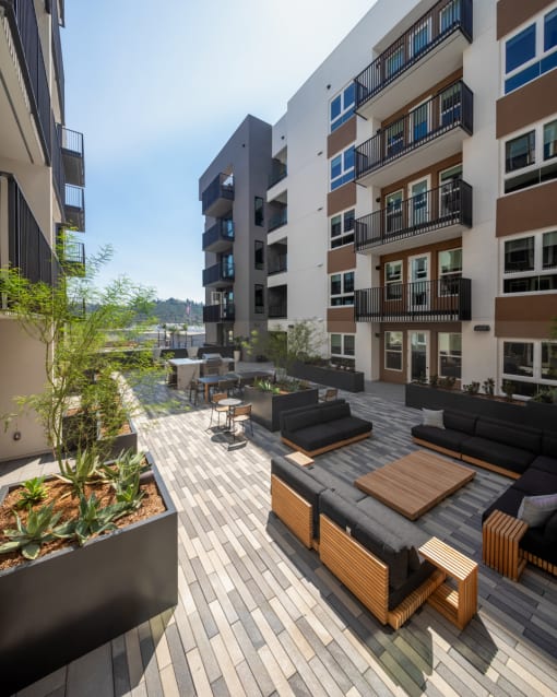 an image of an apartment patio with wooden furniture and potted plants at VORA LUX, San Diego, CA