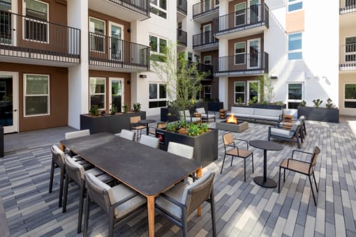 an outdoor patio with tables and chairs at the bradley braddock road station apartments at VORA LUX, San Diego, 92120