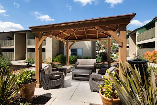A wooden pergola with a patio furniture set underneath it.