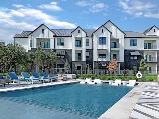 A large white and black building with a pool in front.