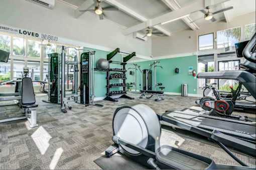 A gym with a variety of equipment including treadmills, weights, and exercise machines.