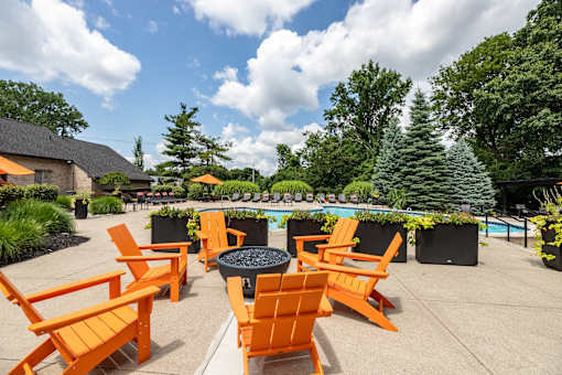 an outdoor patio with orange chairs and a fire pit and a pool