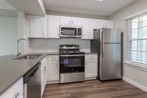 an empty kitchen with white cabinets and stainless steel appliances