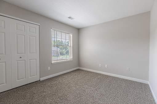 an empty room with carpet and a door and window
