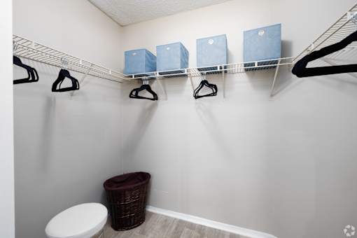 A laundry room with a toilet and a clothes drying rack.