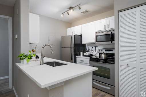 A modern kitchen with a white countertop and stainless steel appliances.