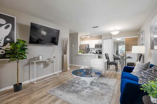 A modern living room with a blue sofa and a flat screen TV mounted on the wall.