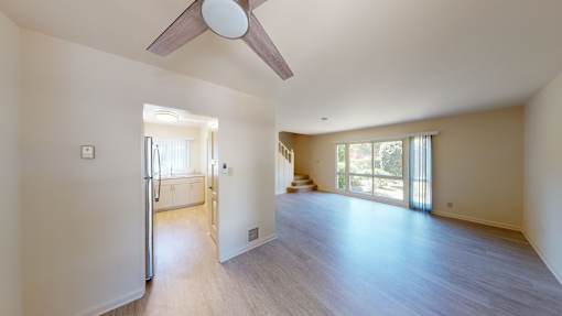 A spacious room with a ceiling fan and sliding glass doors.