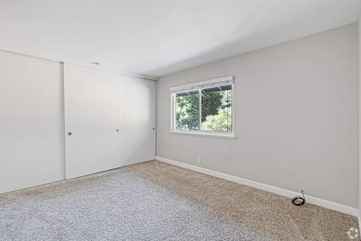 A room with a carpeted floor, a window, and a door.