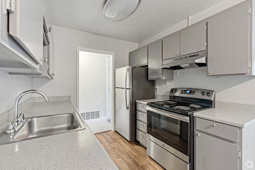 A kitchen with a stainless steel refrigerator, oven, and sink.