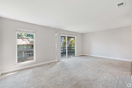 A room with a carpeted floor and a window overlooking a balcony.