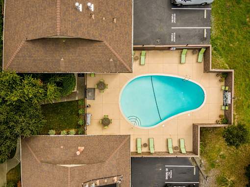 A swimming pool surrounded by a grassy area and a building with a brown roof.