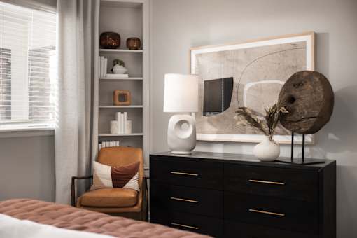 A modern bedroom with a brown chair and a white lamp.