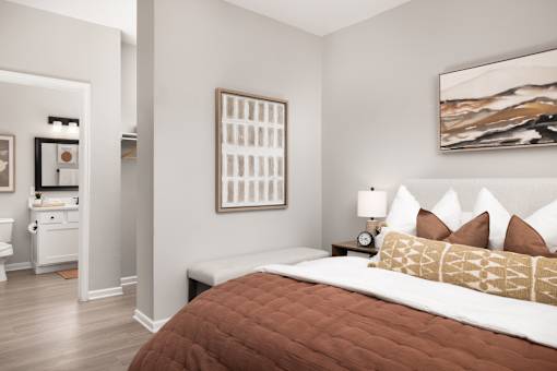 A bedroom with a brown comforter and a painting on the wall.