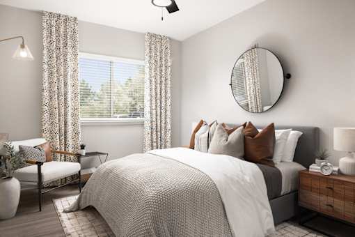 A bedroom with a large bed, a chair, a table, a lamp, and a mirror.