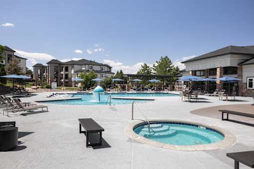 A large outdoor swimming pool with a hot tub and lounge chairs.