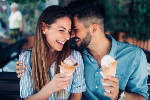 couple eating ice cream together on a park bench