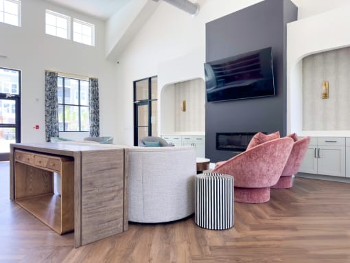 Clubhouse with a couch, tables, a tv hanging on the wall with wood flooring.