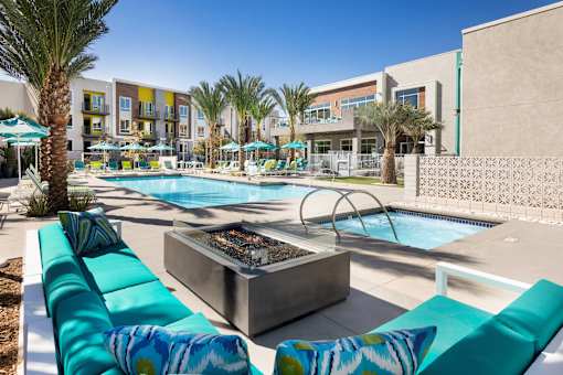 A pool area with a fire pit and lounge chairs.