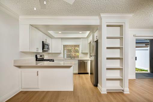 A white kitchen with a microwave and stainless steel appliances.