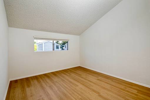 A bedroom with hardwood floors and a window.