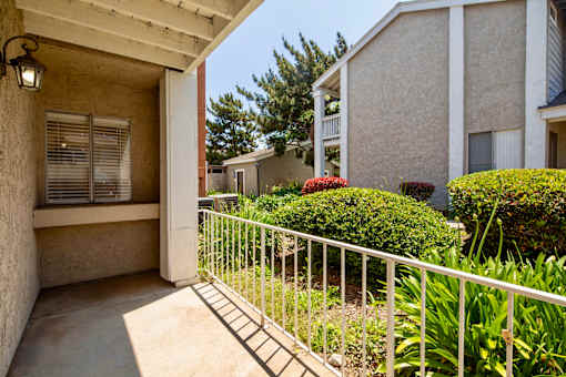 A patio with a white railing and a wall with a window.