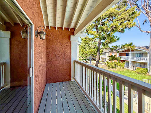 A balcony with a wooden floor and a white railing.