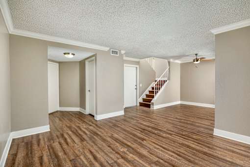 A living room with hardwood floors and a staircase and ceiling fan.