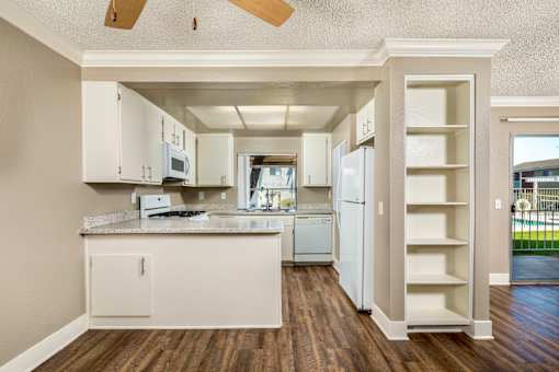 A kitchen with white cabinets and a wooden floor.