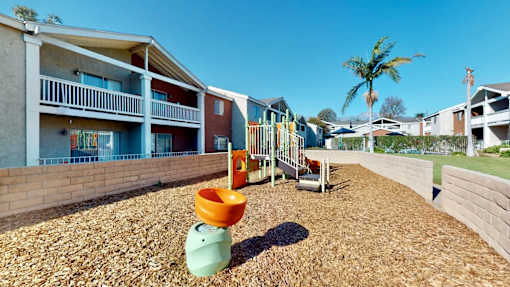 A playground with a slide and a green toy in the foreground.