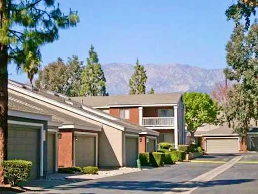 A row of townhouses with garages and trees with a mountain view.