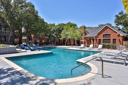 A swimming pool surrounded by lounge chairs and trees.