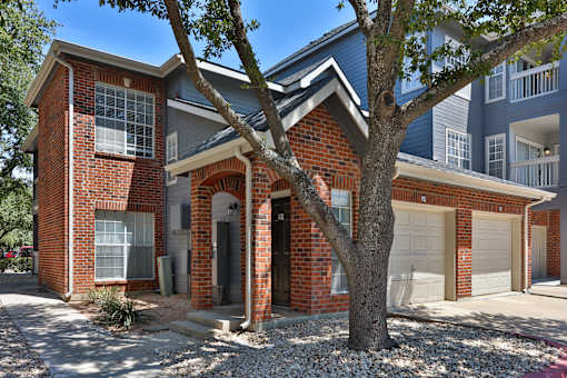 A red brick house with a tree in front.