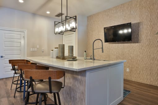 a kitchen with a large island with stools and a tv on the wall at The Quarry Alamo Heights, San Antonio, TX, 78209