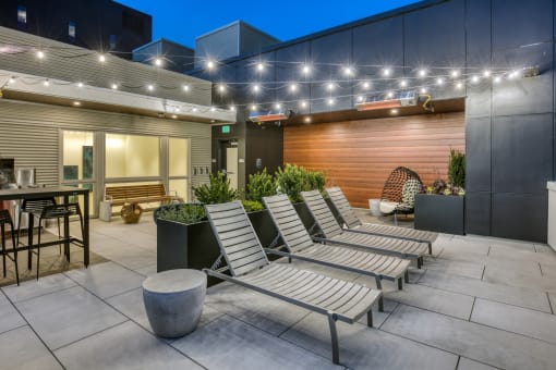 a group of lounge chairs in front of a building with lights on it