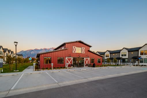 a red barn with a parking lot in front of some houses