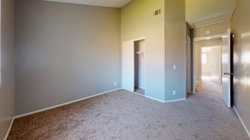 A carpeted room with a door and a window.