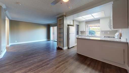 A kitchen with a refrigerator, sink, and cabinets.