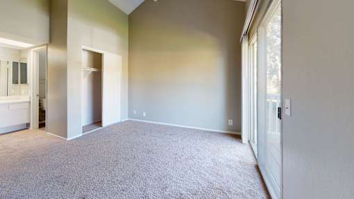 A large, empty room with carpeted flooring and white walls.