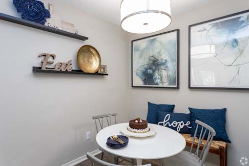 a dining area with a round table and chairs and pictures on the wall