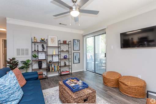 a living room with a ceiling fan and a tv