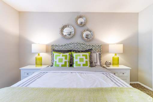 a bedroom with a bed and two mirrors on the wall