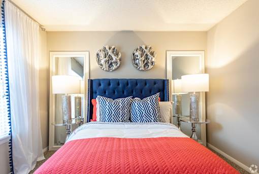a bedroom with a red bed and two mirrors on the wall