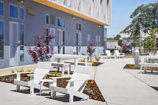 A row of white chairs are lined up on a sidewalk.