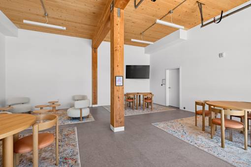 A room with a wooden floor and a white wall with a TV on it.