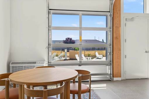 A room with a table and chairs in front of a large window.