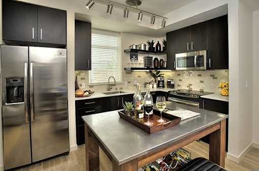 A modern kitchen with a stainless steel refrigerator and a wooden island.